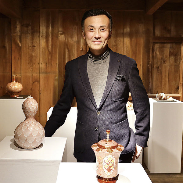 九谷焼赤絵細描の作家・米久 和彦さん。自身の作品が並ぶ展示空間で、赤と金の超絶技巧による唯一無二の器とともに