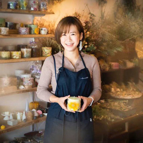 北海道・道南のエシカルキャンドルブランド「710candle」代表・和泉 詩織さん。自社栽培の花を封じ込めたボタニカルキャンドルを手に、店舗にて