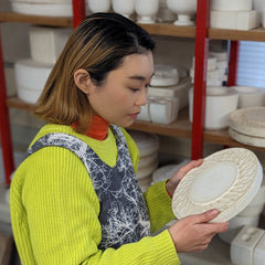 三重県鈴鹿市の陶芸家・畑 直子さん。工房で素焼きの皿を手に取り、フォルムを確かめる。独自の釉薬研究で食卓に彩りをもたらす作家
