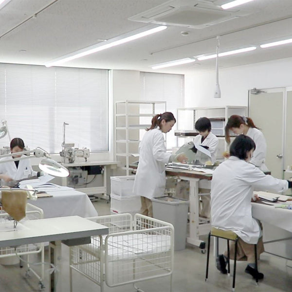 兵庫・豊岡の鞄ブランド「CREEZAN」の白衣着用アトリエ。汚れを防ぐ徹底した品質管理のもと、純白の革バッグを手作業で縫製する職人たち
