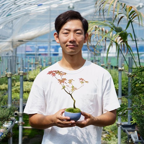 山形県のミニ盆栽ブランド「石木花」常務・後藤 卓也さん。温室で育てた手のひらサイズの紅葉盆栽を両手に。種から商品化まで最低5年をかける